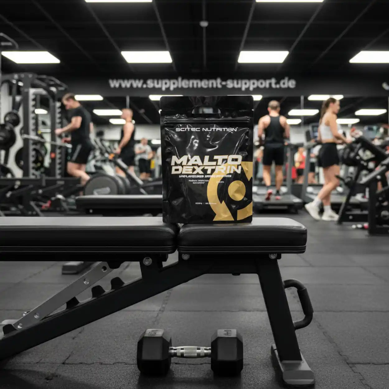 Scitec Nutrition Maltodextrin Packung auf Hantelbank im Fitnessstudio mit Sportlern; Ergänzungsmittel, Sportnahrung, Supplement Support