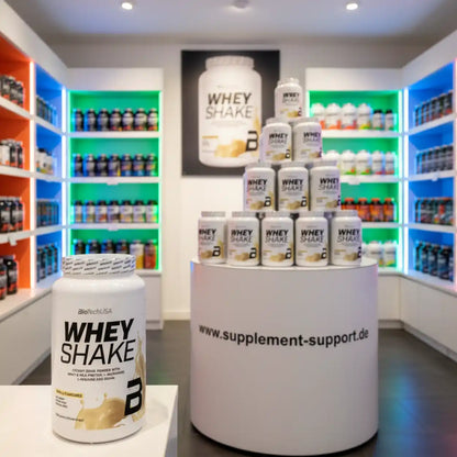 Whey Protein Shake Dose im Nahrungsergänzungsmittel-Geschäft vor beleuchteten Regalen