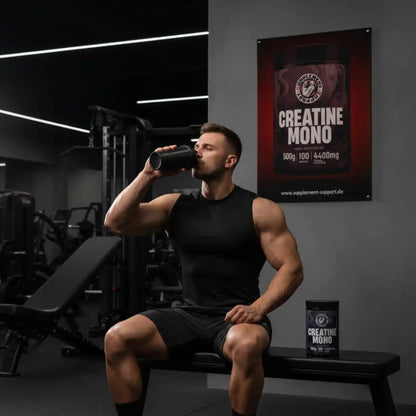 Sportler trinkt Proteinshake im Fitnessstudio neben Creatin Mono Dose, Nahrungsergänzungsmittel