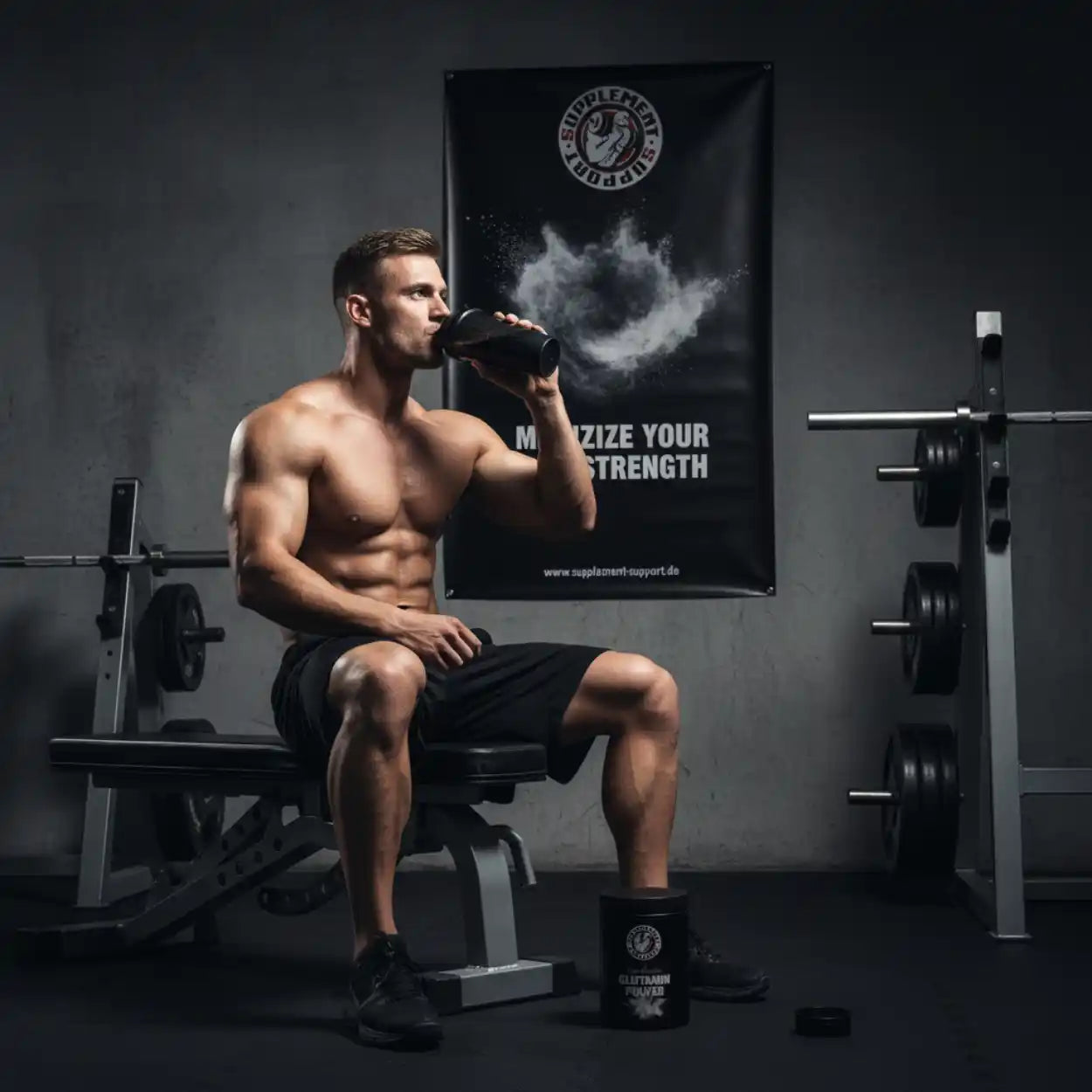 Muskulöser Mann im Fitnessstudio trinkt Proteinshake, Glutamin-Pulver neben Hantelbank