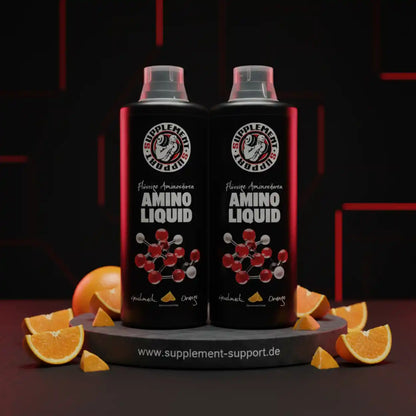 Zwei Flaschen Amino Liquid Nahrungsergänzung Orange mit Orangenscheiben auf schwarzem Hintergrund