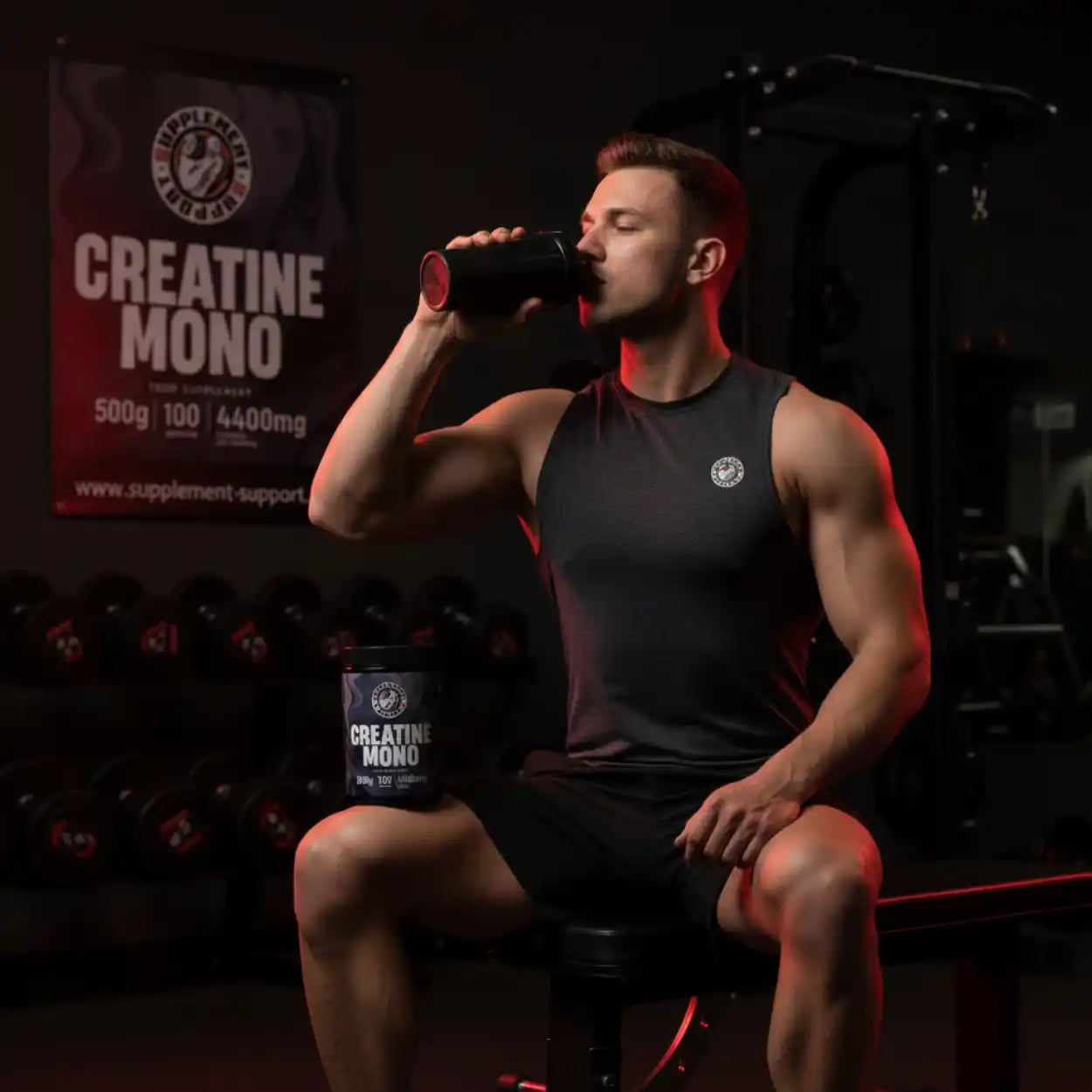 Muskulöser Mann im Fitnessstudio trinkt Creatin Mono Shake, Produktdose im Vordergrund