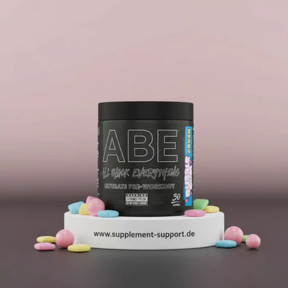ABE Ultimate Pre-Workout Booster Dose in Schwarz mit bunten Zuckerperlen auf weißem Podest
