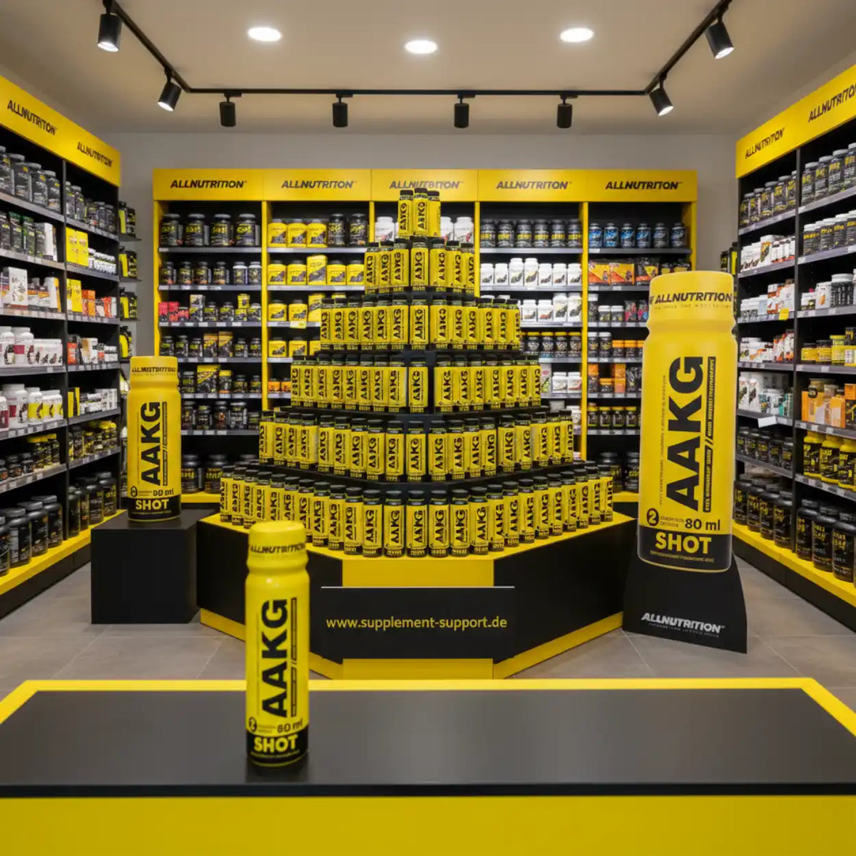 AAKG Shot von AllNutrition in Supplement-Store mit gelben Regalen und Produkten