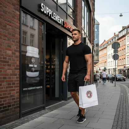 Muskulöser Mann mit Einkaufstüte vor Supplement Support Shop, Amino Tabs im Fenster