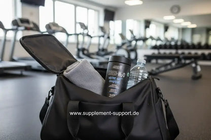 Fitness-Tasche mit Nahrungsergänzungsmittel, Wasserflasche und Handtuch im Gym