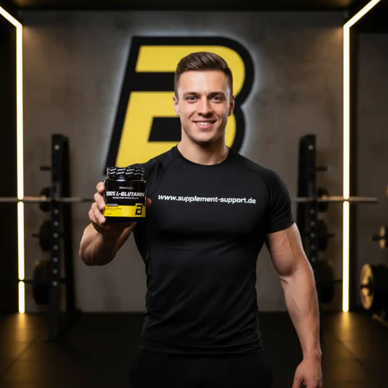 Muskulöser Mann hält 100% L-Glutamin Supplement im Fitnessstudio, ideal für Sportnahrung und Booster