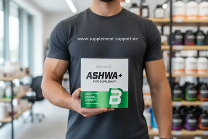 Muskulöser Mann hält Ashwa+ Nahrungsergänzungsmittel von BioTechUSA in Supplement-Shop
