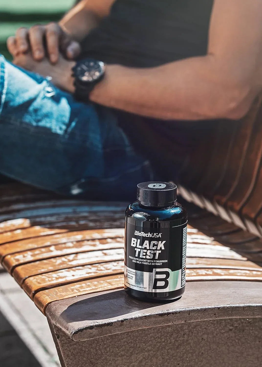BiotechUSA Black Test 90 Kapseln Nahrungsergänzung auf Holzbank, Mann im Hintergrund