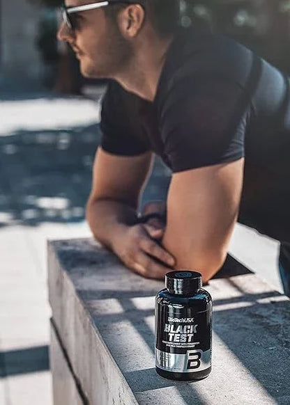 BiotechUSA Black Test 90 Kapseln Nahrungsergänzung auf Stein, Mann im Hintergrund