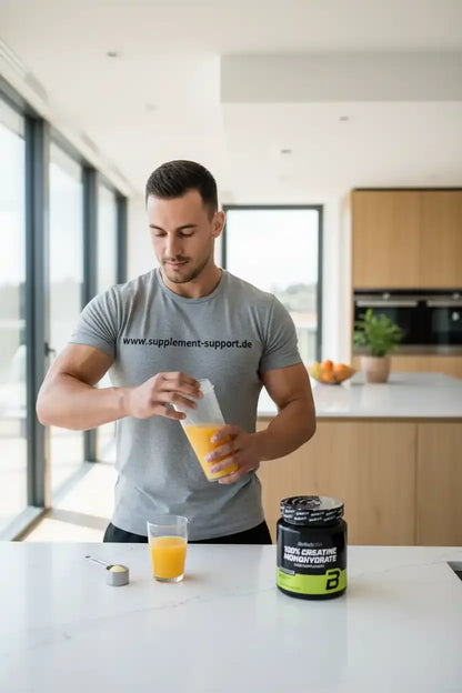 Muskulöser Mann bereitet Kreatin-Monohydrat in Orangensaft zu – Sportnahrung & Booster für Fitness