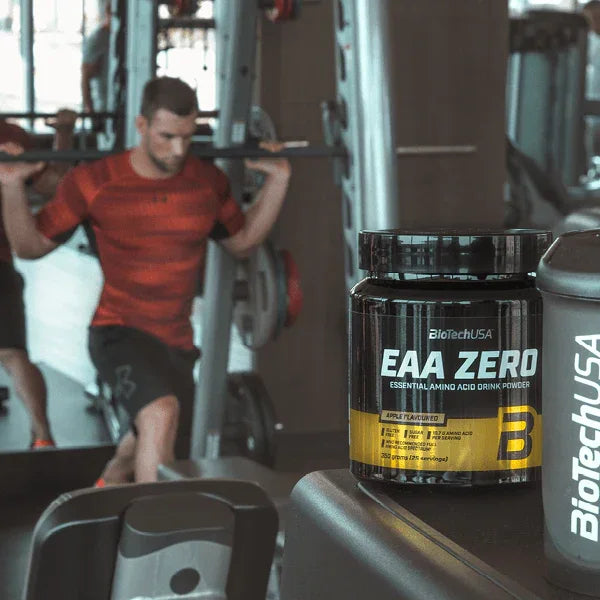 BioTechUSA EAA Zero Aminosäuren Pulver Dose im Fitnessstudio neben Sportler mit Hanteln