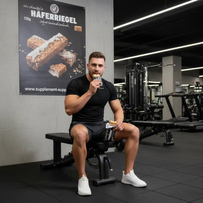 Muskulöser Mann isst Haferriegel im Fitnessstudio – Proteinriegel für Sportler & Training