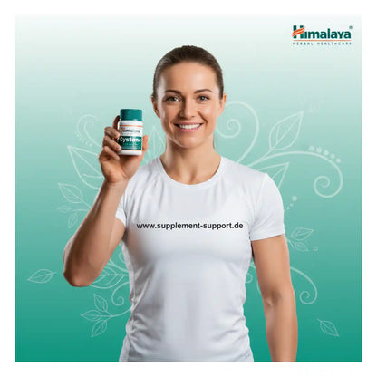 Lächelnde Frau hält eine Dose Himalaya Cystone Nahrungsergänzungsmittel vor hellem Hintergrund.