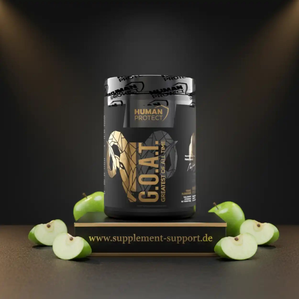 Schwarzer G.O.A.T. Protein-Becher von Human Protect auf einem Podest mit grünen Äpfeln.