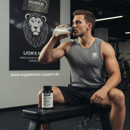 Muskulöser Mann trinkt Proteinshake im Fitnessstudio neben einer Dose Lion's Mane Supplement.