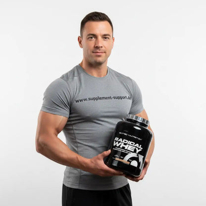 Muskulöser Mann im grauen T-Shirt hält Radical Whey Protein Cookies & Cream von Supplement Support