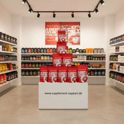 100% Whey Protein in roten Beuteln im Supplement-Shop, Regale mit Nahrungsergänzungsmitteln im Hintergrund
