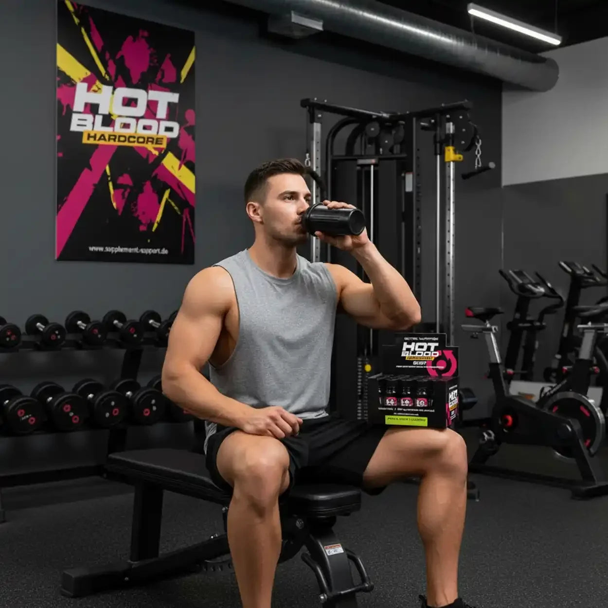 Muskulöser Mann trinkt Hot Blood Hardcore Booster im Fitnessstudio – Protein & Sportnahrung