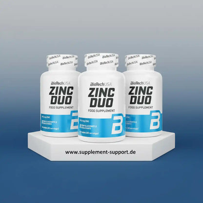 Drei weiße Dosen BioTechUSA Zinc Duo Nahrungsergänzungsmittel auf einem weißen Podest.